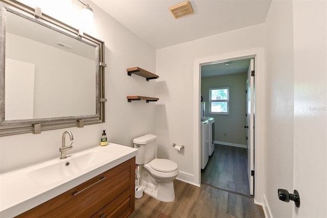 4520 Wescott Ln, Tampa, FL 33624 - bathroom featuring washing machine and clothes dryer, wood finished floors, baseboards, toilet, and visible vents