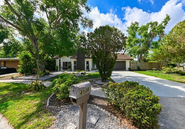 4520 Wescott Ln, Tampa, FL 33624 - view of property hidden behind natural elements featuring fence, an attached garage, stucco siding, and concrete driveway