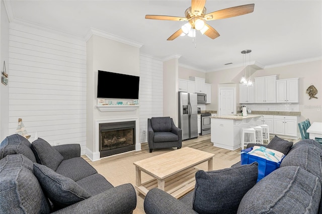 living room featuring a fireplace, light wood finished floors, ceiling fan, and ornamental molding