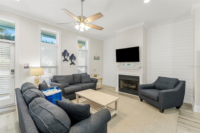 living room with recessed lighting, a fireplace, a ceiling fan, light wood-style flooring, and ornamental molding