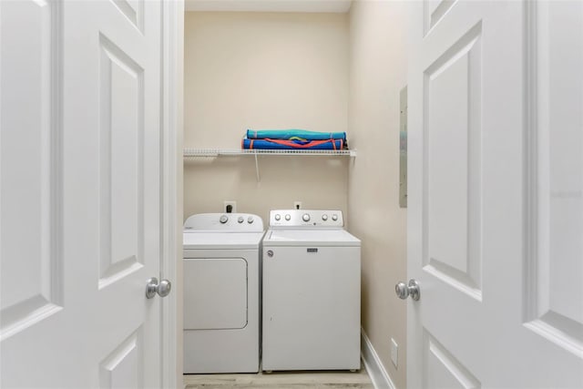 clothes washing area featuring light wood-type flooring, washing machine and clothes dryer, and laundry area