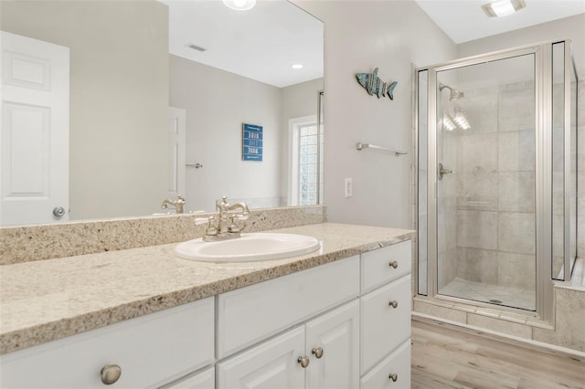 bathroom with vanity, visible vents, a shower stall, and wood finished floors