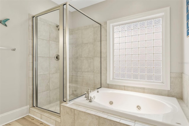 bathroom with a whirlpool tub, a stall shower, and wood finished floors