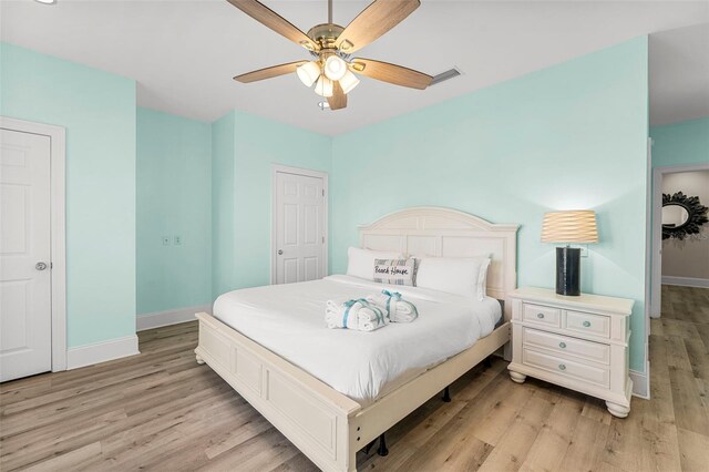 bedroom with baseboards, visible vents, ceiling fan, and light wood-style flooring