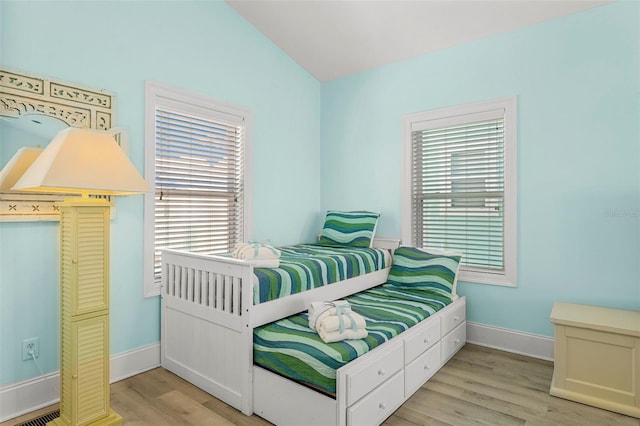 bedroom with baseboards, vaulted ceiling, and light wood-style floors