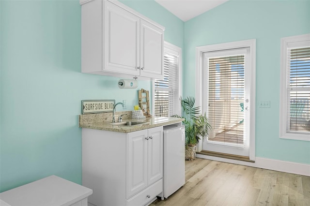 interior space featuring baseboards, light wood finished floors, and a sink