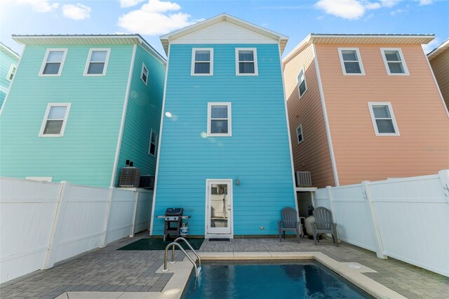 rear view of house featuring a patio, a fenced backyard, and a fenced in pool