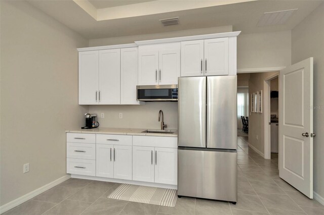 3504 Golden Wheat Ln, Plant City, FL 33565 - kitchen featuring appliances with stainless steel finishes, a sink, light tile patterned flooring, and white cabinetry