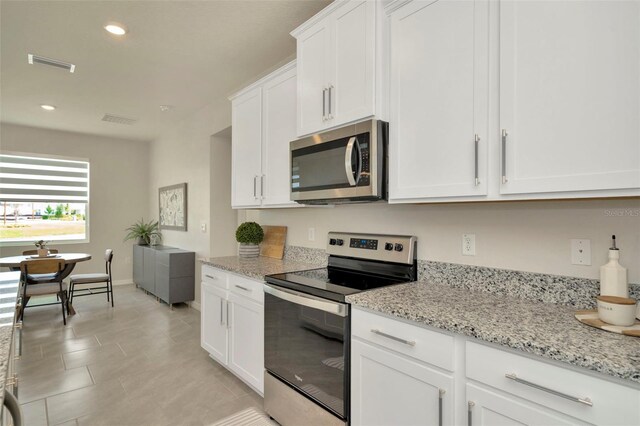 3504 Golden Wheat Ln, Plant City, FL 33565 - kitchen featuring appliances with stainless steel finishes, white cabinets, recessed lighting, and light stone countertops