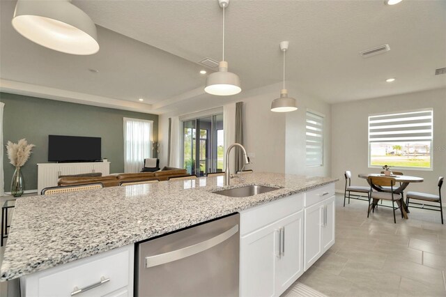 3504 Golden Wheat Ln, Plant City, FL 33565 - kitchen featuring stainless steel dishwasher, a sink, open floor plan, light stone countertops, and white cabinets
