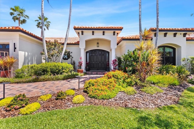 mediterranean / spanish home featuring a tiled roof and stucco siding