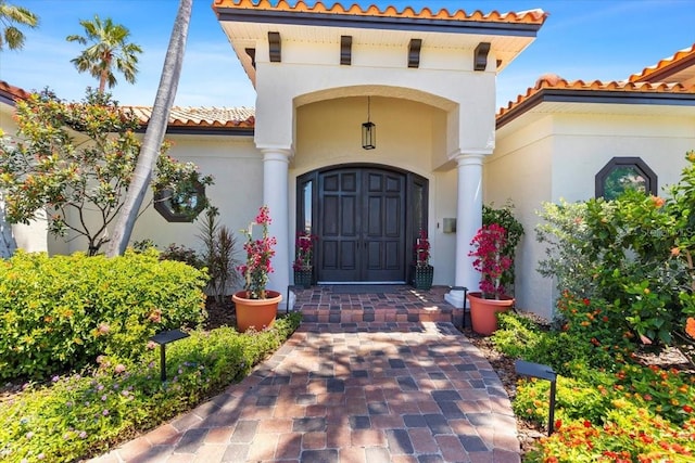 doorway to property featuring a tile roof and stucco siding