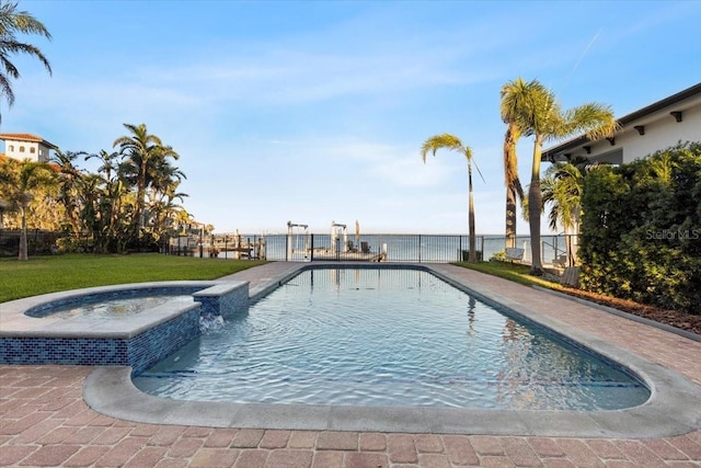 view of swimming pool featuring fence, a lawn, a pool with connected hot tub, and a water view