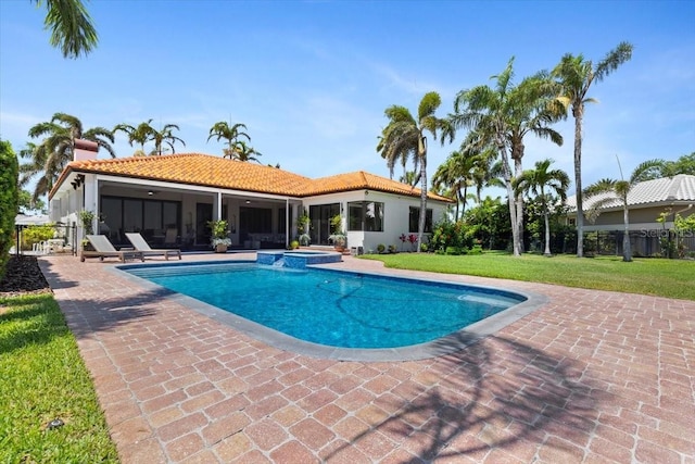 view of swimming pool featuring a lawn, fence, a patio, and a pool with connected hot tub