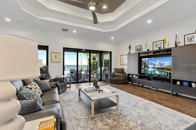 living room featuring visible vents, a raised ceiling, and ornamental molding