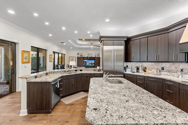 kitchen with a large island, a sink, light wood-style floors, crown molding, and appliances with stainless steel finishes