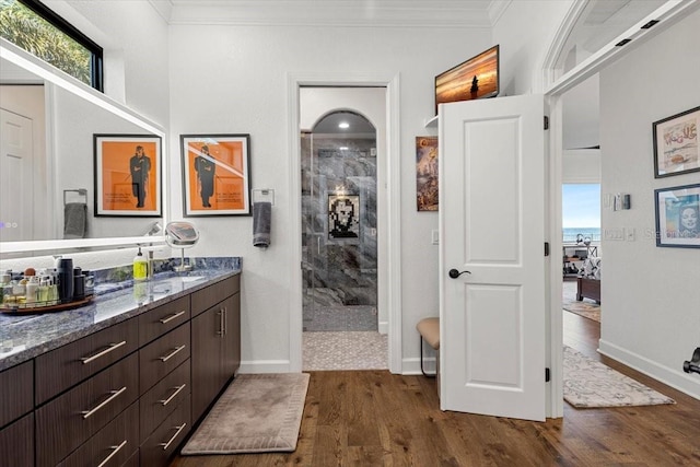 ensuite bathroom with crown molding, wood finished floors, and a walk in shower