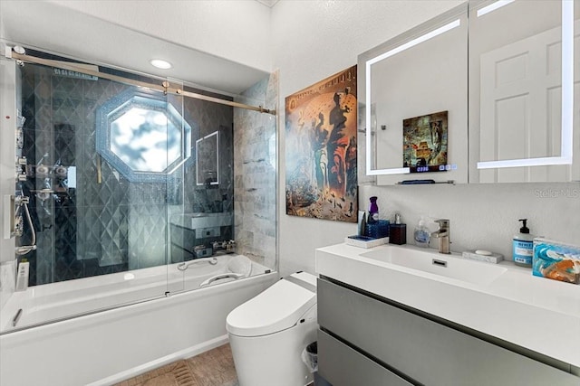 bathroom with vanity, shower / bath combination with glass door, and toilet