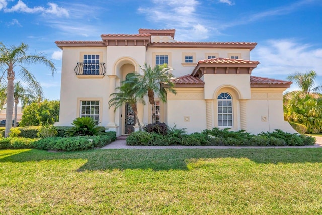 mediterranean / spanish-style home with a front lawn, stucco siding, and a tile roof