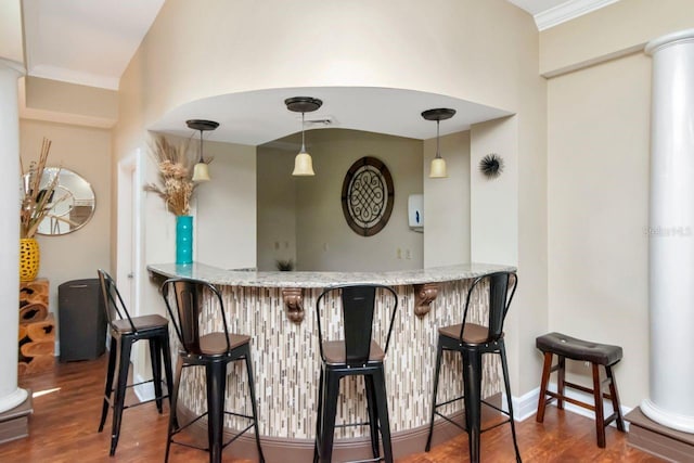 bar featuring decorative light fixtures, wood finished floors, bar area, and decorative columns