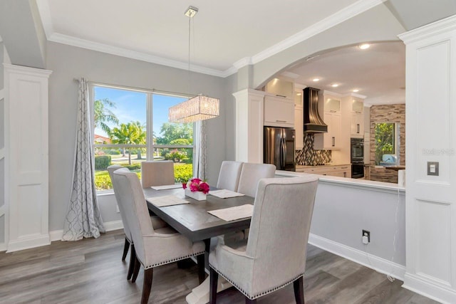 dining room featuring dark wood finished floors, baseboards, arched walkways, and crown molding