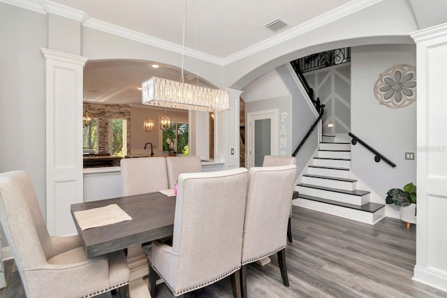 dining room featuring arched walkways, wood finished floors, stairs, visible vents, and a notable chandelier