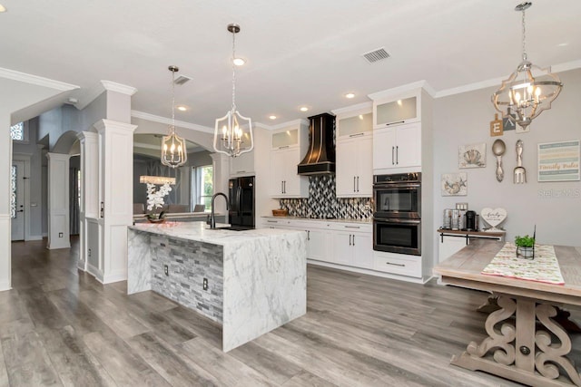 kitchen with an inviting chandelier, custom range hood, freestanding refrigerator, and visible vents