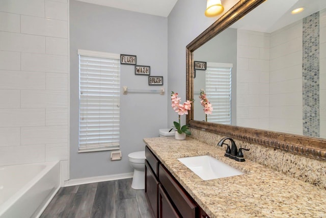 bathroom with wood finished floors, vanity, toilet, and baseboards