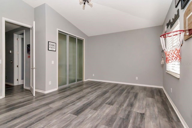 empty room featuring baseboards, wood finished floors, and vaulted ceiling