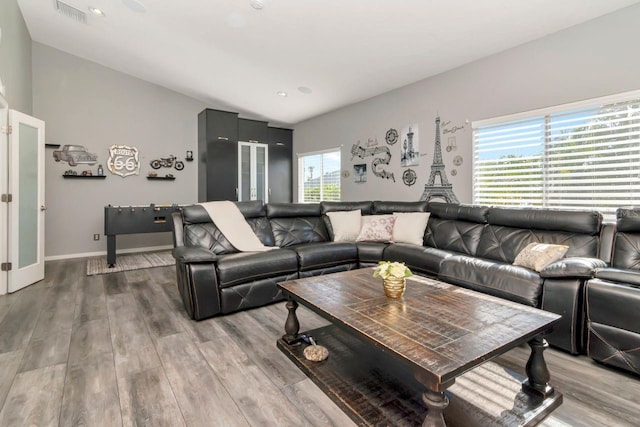 living area with lofted ceiling, visible vents, light wood finished floors, and baseboards