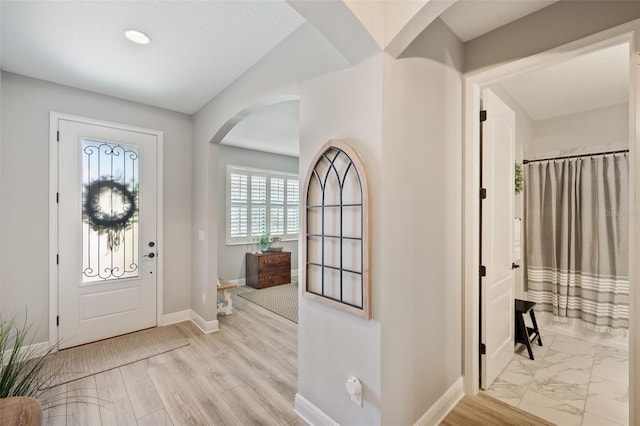 entrance foyer featuring arched walkways and baseboards