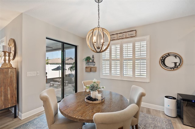 dining space with baseboards, a chandelier, and light wood-style flooring