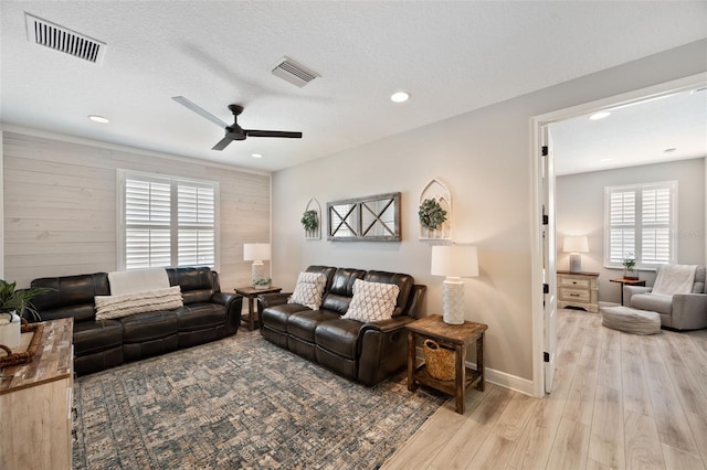 living area featuring ceiling fan, baseboards, light wood finished floors, and visible vents