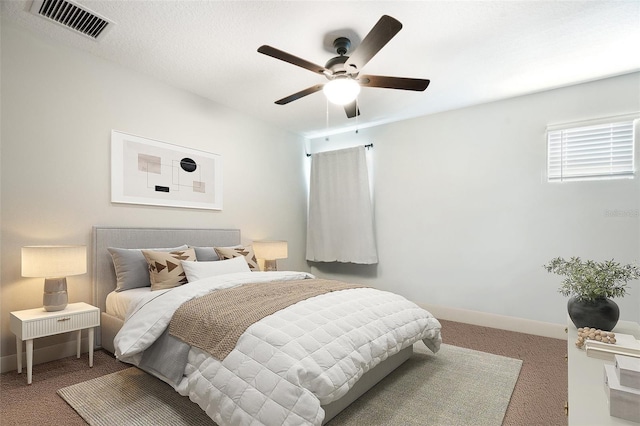 carpeted bedroom with baseboards, a ceiling fan, and visible vents