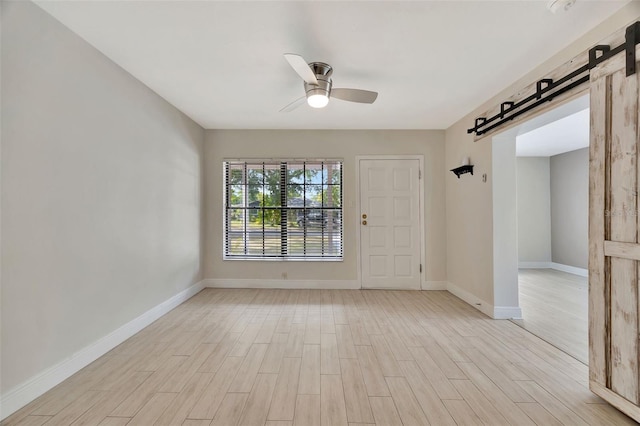 unfurnished room with light wood-type flooring, a ceiling fan, and baseboards