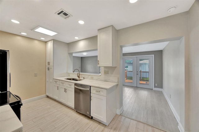 kitchen featuring baseboards, dishwasher, visible vents, and a sink
