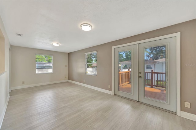 unfurnished room with a wealth of natural light, french doors, and light wood-type flooring