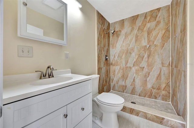 full bath with toilet, vanity, and a tile shower