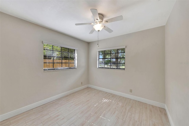 empty room with wood finished floors, a ceiling fan, and baseboards
