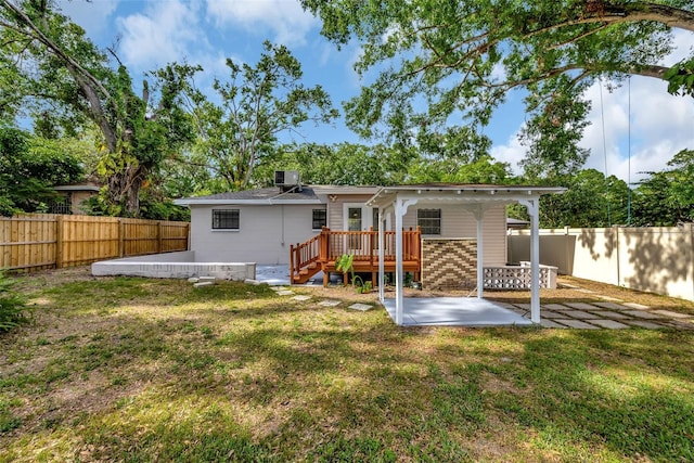 rear view of property featuring a fenced backyard, a deck, a patio, and a lawn
