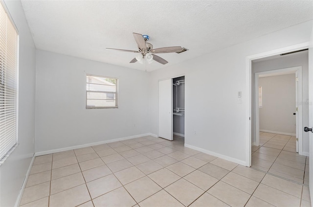 unfurnished bedroom featuring a closet, ceiling fan, baseboards, a textured ceiling, and light tile patterned flooring