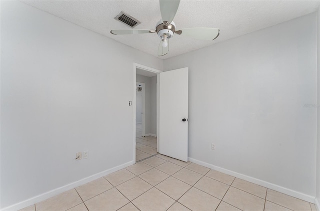 unfurnished room with light tile patterned floors, a textured ceiling, visible vents, baseboards, and a ceiling fan