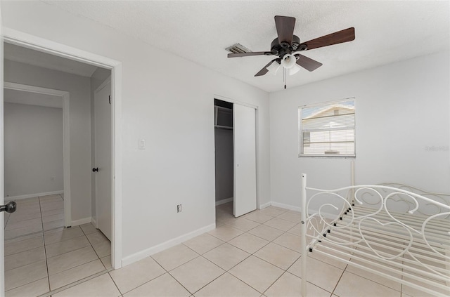 bedroom featuring visible vents, baseboards, a closet, light tile patterned flooring, and a ceiling fan