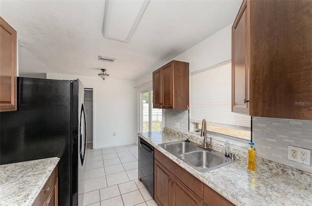 kitchen featuring light tile patterned floors, black appliances, a sink, and decorative backsplash