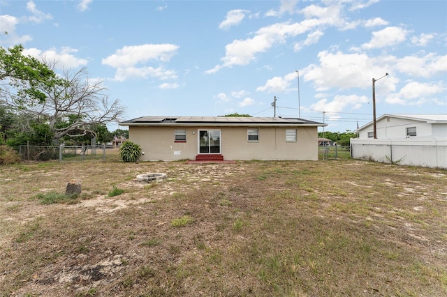 222 Aldo Dr, Babson Park, FL 33827 - rear view of property featuring entry steps, roof mounted solar panels, a fenced backyard, and an outdoor fire pit