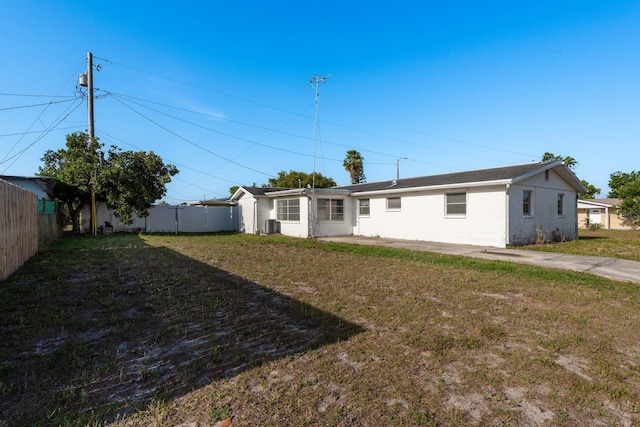 back of property with a lawn, fence, and central AC unit