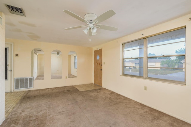 unfurnished room with arched walkways, ceiling fan, visible vents, and carpet