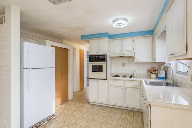 kitchen featuring backsplash, a sink, light countertops, light floors, and white appliances