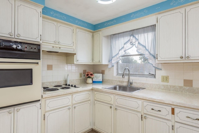 kitchen with white appliances, decorative backsplash, a sink, and light countertops