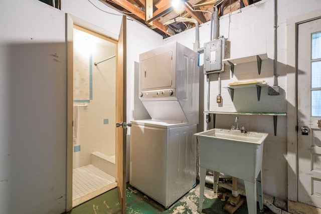 clothes washing area featuring laundry area, stacked washer and dryer, and electric panel